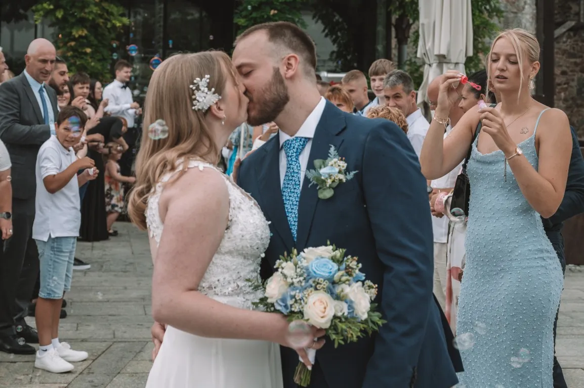 Poročna fotografija mladoporočencev; ujet pristen trenutek z naravno svetlobo in umirjeno kompozicijo v dokumentarnem slogu.